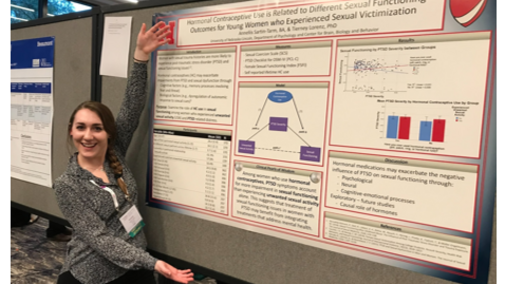 Researcher gesturing enthusiastically toward a scientific poster in a conference setting.